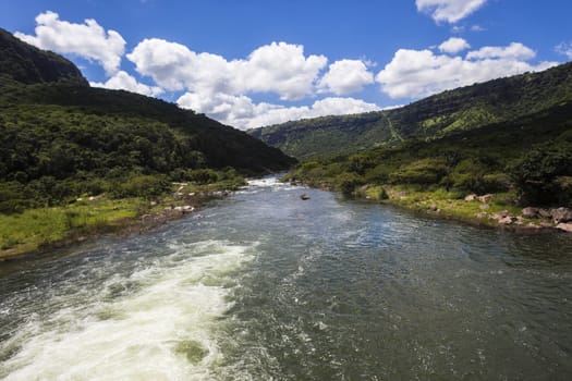 River water flowing down the green summer valley landscape