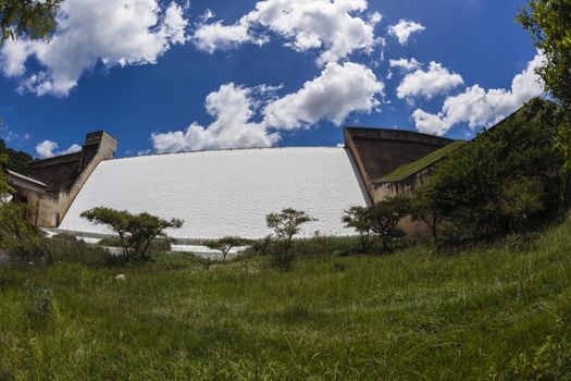 Power and energy of water volumes over Dam  wall into green valley