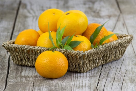 fresh tangerines in a basket on old wooden background