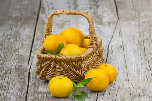 fresh tangerines in a basket on old wooden background