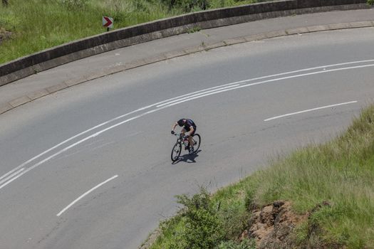 Unidentified, cyclist mtb bike training climbing out of steep twisting valley roads.