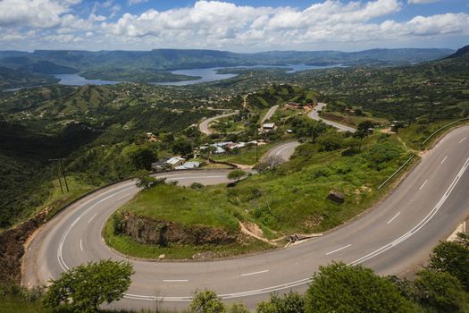 Dam waters green valley with twisting winding road on a summers day.