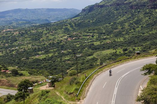 Cyclist training climbing out of green valleys winding twisting roads