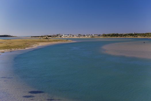 Blue river channels through sandbanks towards distant ocean