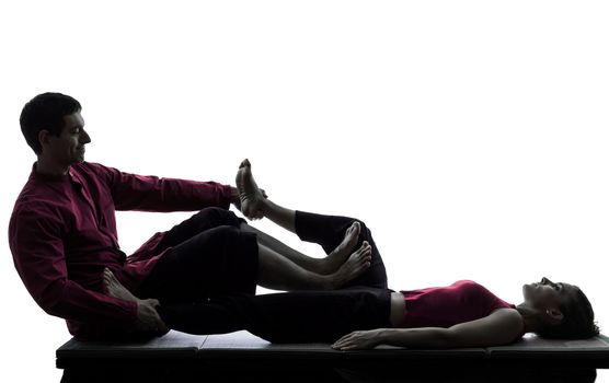 one man and woman performing feet legs thai massage in silhouette studio on white background