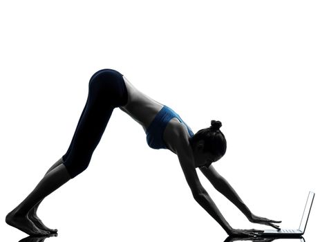 one caucasian woman exercising yoga using computer laptop in silhouette studio isolated on white background