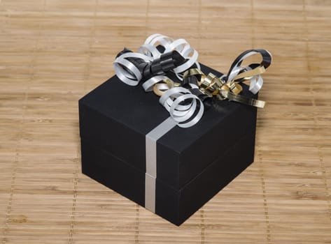 black box with white lines and golden silver bows as present