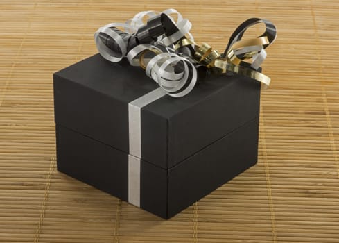 black box with white lines and golden silver bows as present