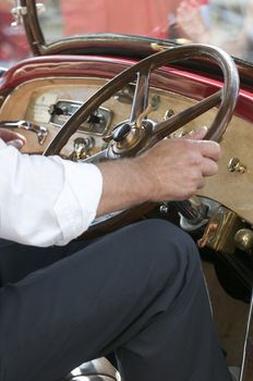 Detail of man driving a vintage car with hand on steering wheel