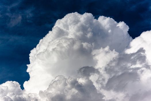 Summer storm thick white clouds cumulous against dark blue sky.