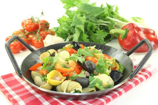 Pasta pan with bell pepper and turnip greens on a light background