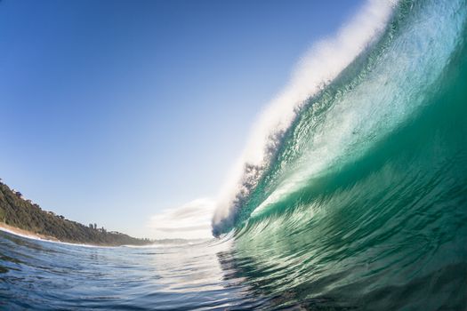 Swimming view of ocean wave lip in detail crashing towards shallow reef in morning light.