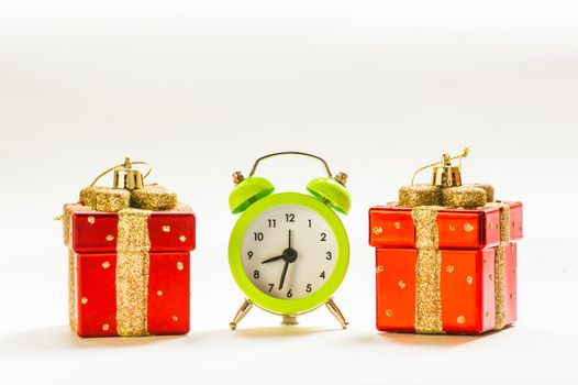 Green alarm clock between two present shaped Christmas decorations
