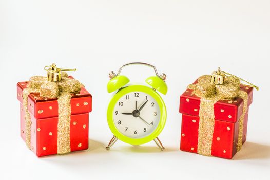 Green alarm clock between two present shaped Christmas decorations
