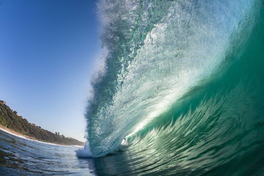 Swimming view of ocean wave lip in hollow detail crashing towards shallow reef in morning light.