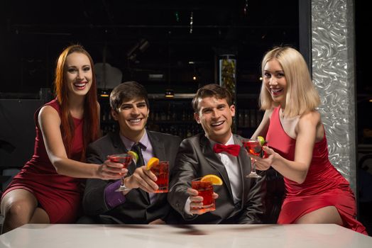 Men and women raised their glasses with cocktails in a nightclub, a party with friends
