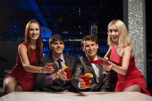 Men and women raised their glasses with cocktails in a nightclub, a party with friends