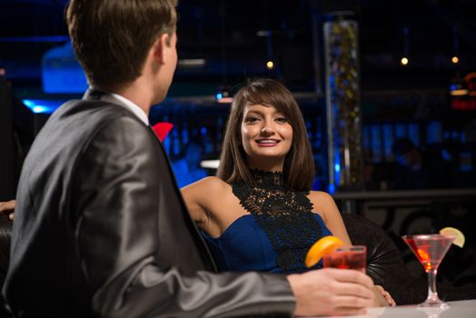 portrait of a woman in a nightclub, sitting on the couch and talking with man