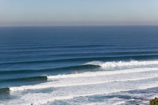 Large ocean coming in from deep blue sea horizon and crashing breaking on shallow reefs with shape and power.