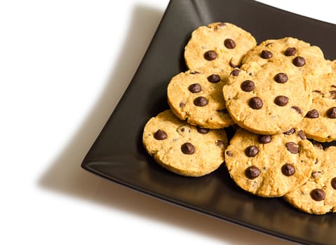 Closeup of chocolate chip cookies on a square black plate, isolated on white background