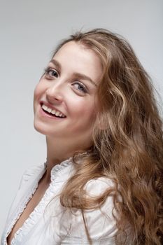 portrait of a young beautiful woman with brown hair smiling - isolated on gray