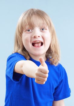 boy with long blond hair showing thumbs up sign - isolated on blue