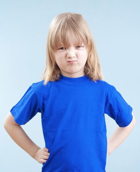 angry boy with long blond hair standing looking - isolated on blue