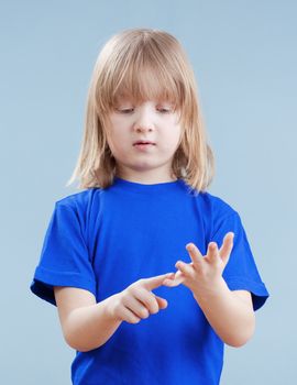 boy with long blond hair counting on fingers of his hand - isolated on blue