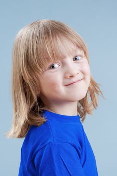 studio portrait of a boy with long blond hair - isolated on blue