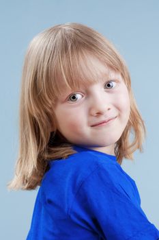 studio portrait of a boy with long blond hair - isolated on blue