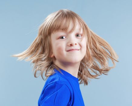 studio portrait of a boy with long blond hair - isolated on blue