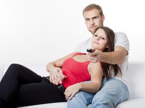 young couple sitting on sofa at home watching television