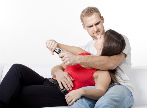 young couple watching television, fighting over remote control