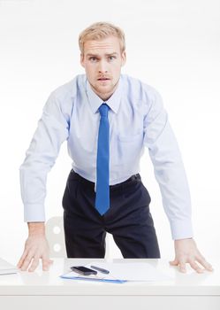 serious boss sitting behind desk at office looking at camera