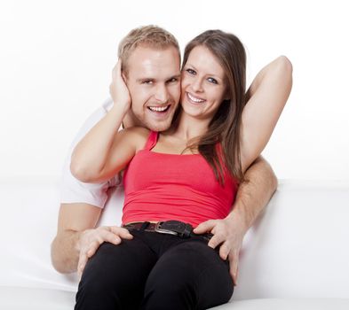 portrait of a happy young couple sitting, embracing, smiling, looking
