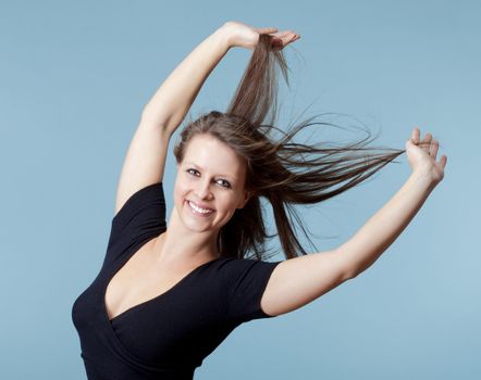 young beautiful woman with brown hair smiling - isolated on blue