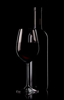 Glass and bottle of red wine on black background