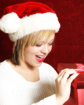 An attractive young woman opens a gift on Chrsitmas.