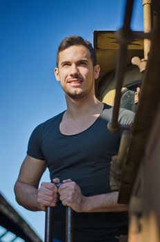 Handsome young man holding from old train handle, looking far