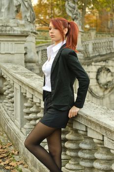 Pretty young woman in business attire outdoors against stone banister