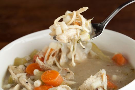 Closeup of a spoonful of fresh homemade traditional chicken soup. Shallow depth of field.