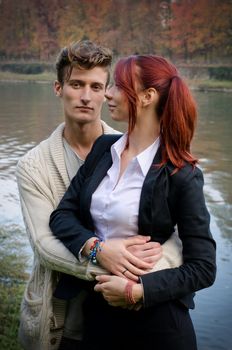 Romantic young couple, man holding woman in his arms, near river water