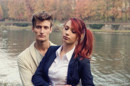 Romantic young couple, man holding woman in his arms, near river water