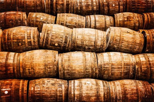 Stacked pile of old whisky and wine wooden barrels in vintage style