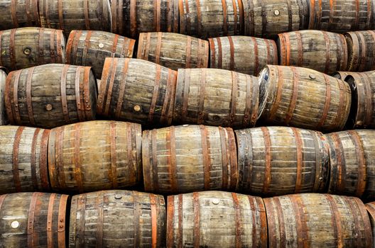 Stacked pile of old whisky and wine wooden barrels and casks