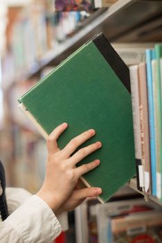 Student putting a green book back onto a bookshelf in library