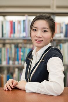 Young student resting on a wooden shelf in front of a bookshelf in library