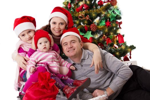 Happy family with two little daughters under Chritmas tree over white