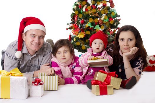 Happy family with two little daughters lying under Christmas tree over white