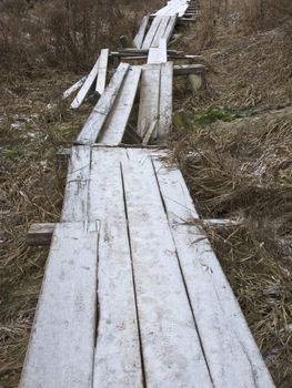 Destroyed wooden footway with hoarfrost in ravine